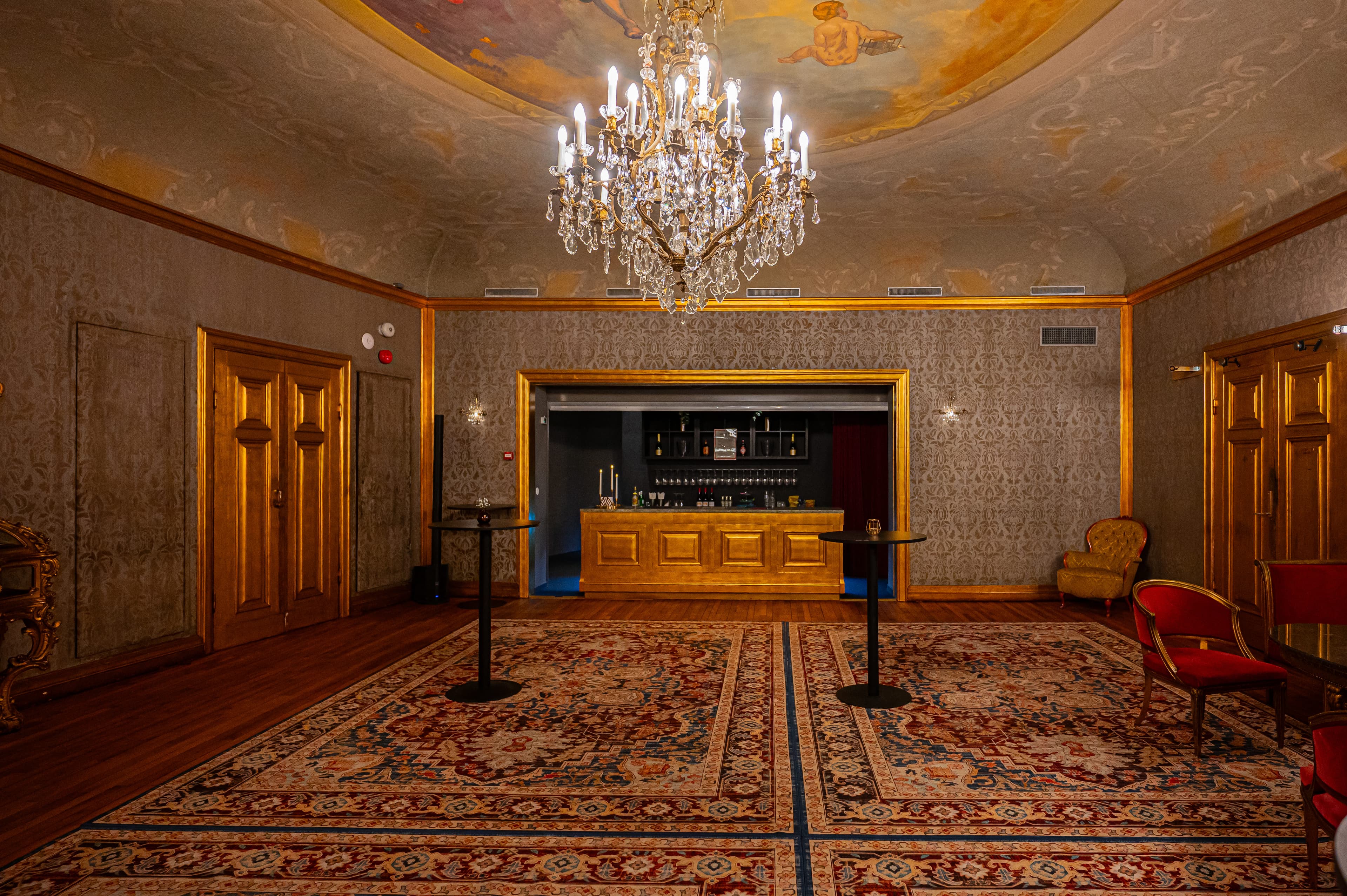 The Gold Foyer's gilded bar beneath ceiling murals and a crystal chandelier