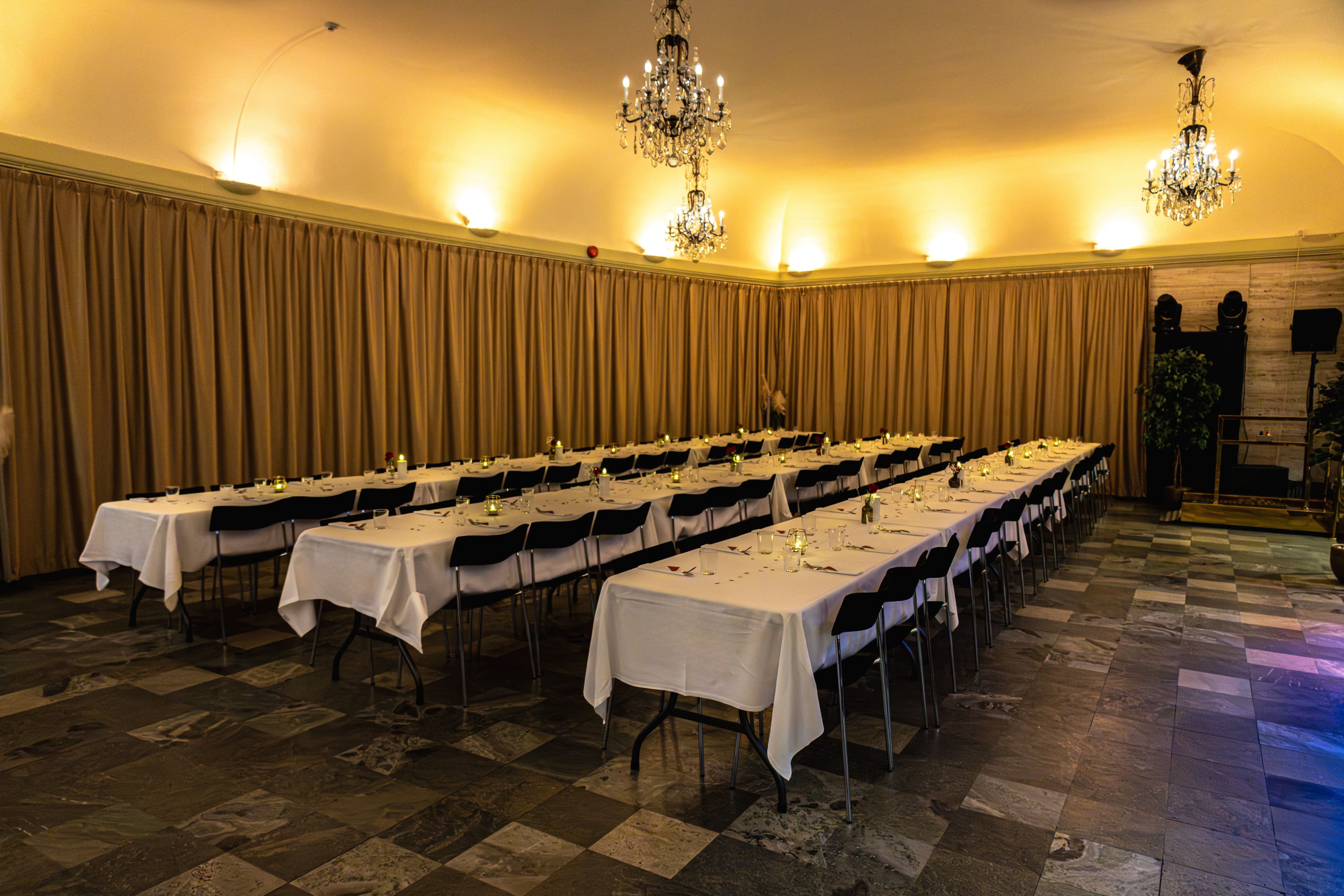 Long tables set for dinner beneath crystal chandeliers in The Marble Foyer